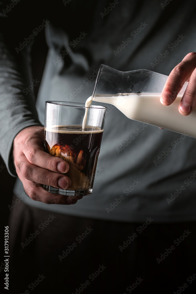 Man adds milk to black coffee Man adds milk to black coffee