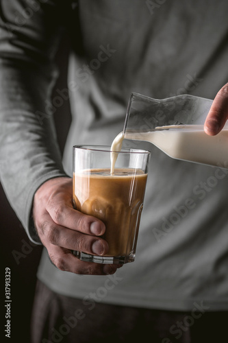 Man adds milk to black coffee