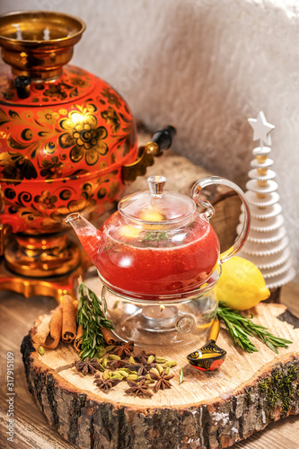 Hot fruit red berry tea with steam in the teapot with mint, berries, lemon slices on wooden background. Food and drink. New year holidays, christmas xmas dinner concept