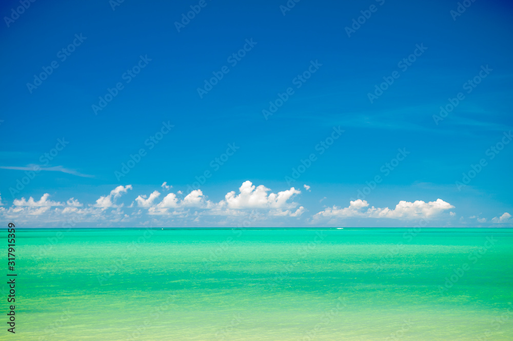 Obraz premium Tropical sea background in vibrant hues of turquoise blue with low clouds on the horizon