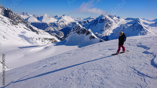 Cool female snowboarder looks at the mountains before going on an off piste run