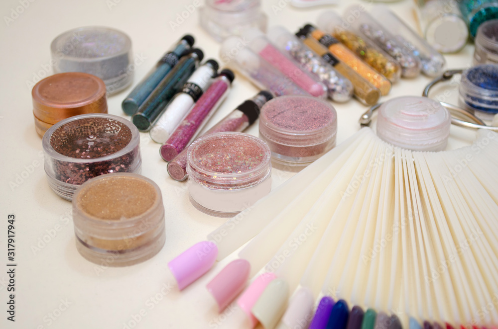Naklejka premium Jars with sparkles and decor for nail design, color samples of gel polish on a plastic tips closeup