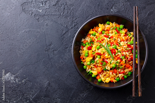 Asian fried rice with egg and vegetables. Black background. Cope space. Top view.
