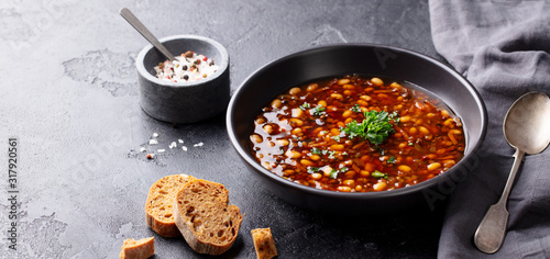 Fototapeta Naklejka Na Ścianę i Meble -  Bean soup in a black bowl. Black background. Copy space.