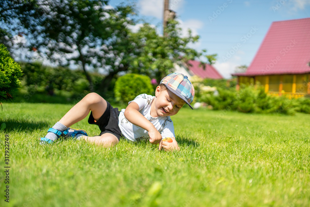 Obraz premium a little boy is lying on the grass and holding a pear
