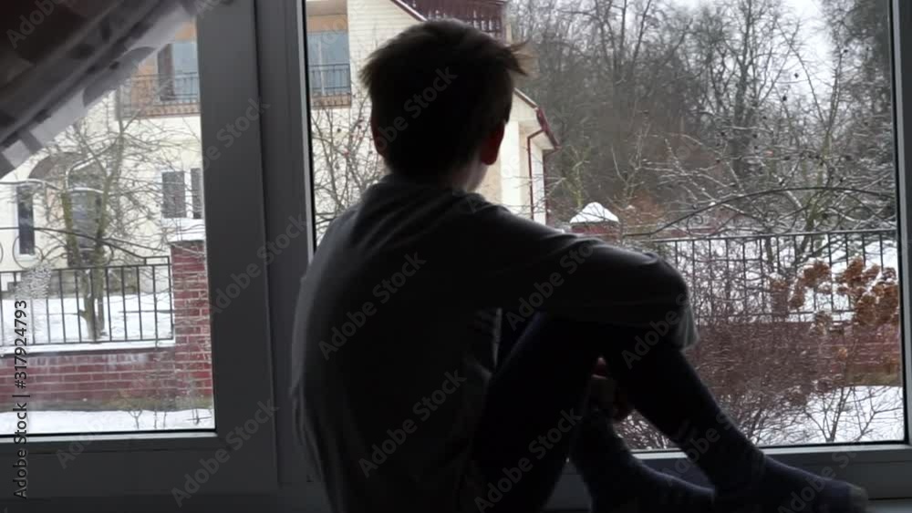 quarantine time at School. home isolation from virus. child kid sitting on the window sill and looking through the window on falling snowflakes. sick boy wants to go outdoor to play quarantine time at School. home isolation from virus. child kid sitting on the window sill and looking through the window on falling snowflakes. sick boy wants to go outdoor to play