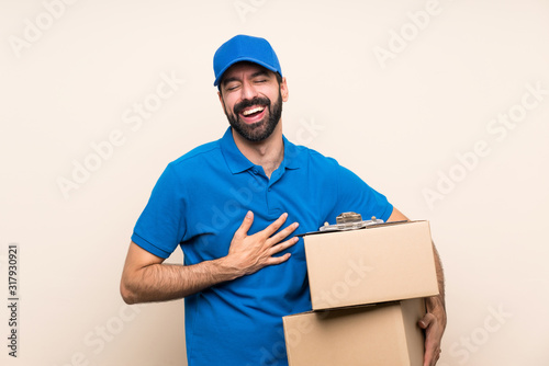 Delivery man with beard over isolated background smiling a lot