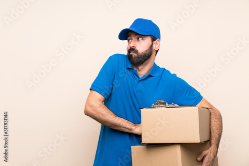 Delivery man with beard over isolated background making doubts gesture while lifting the shoulders © luismolinero