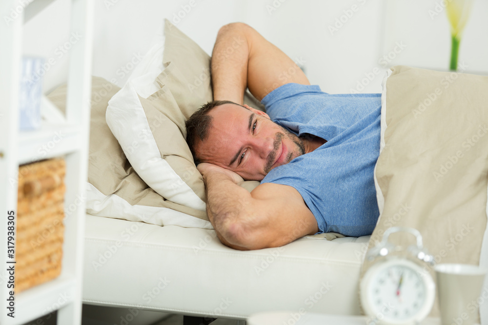 portrait of man stretching and smiling while layed in bed portrait of man stretching and smiling while layed in bed