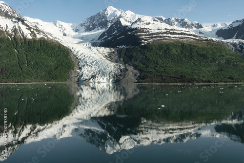 Reflection In The Water Of High Snow Capped Mountain Range With Glacier At College Fjord, Alaska
