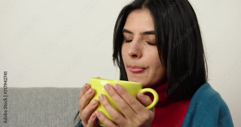 Brunette sitting on the sofa with plaid and drink cup of tea, relaxing, Girl in the plaid.Thought Brunette sitting on the sofa with plaid and drink cup of tea, relaxing, Girl in the plaid.Thought