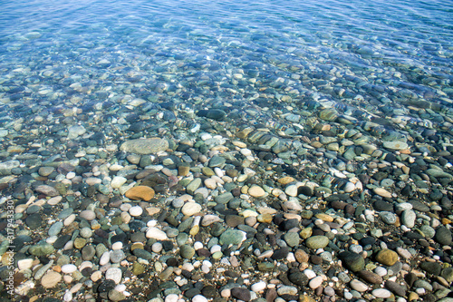 Sea stones in sea water. Pebbles under water. The view from the top. Nautical background. Clean sea water. Transparent sea