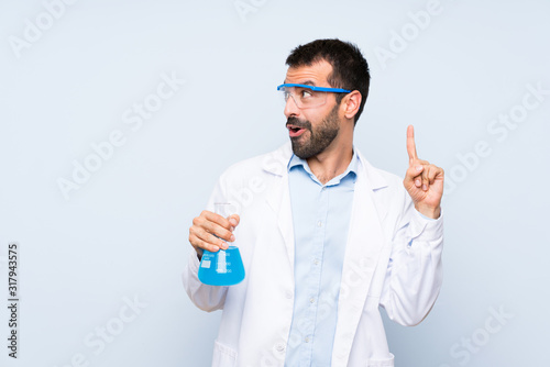 Young scientific holding laboratory flask over isolated background intending to realizes the solution while lifting a finger up