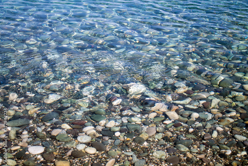 Sea stones in sea water. Pebbles under water. The view from the top. Nautical background. Clean sea water. Transparent sea