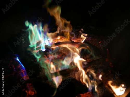 Feuer in grosser Feuerschale mit gelben, gruenen und blauen Flammen und roter Glut