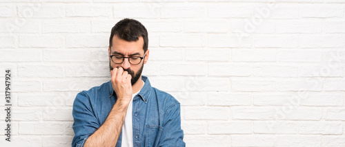 Fotografie Handsome man with beard over white brick wall having doubts