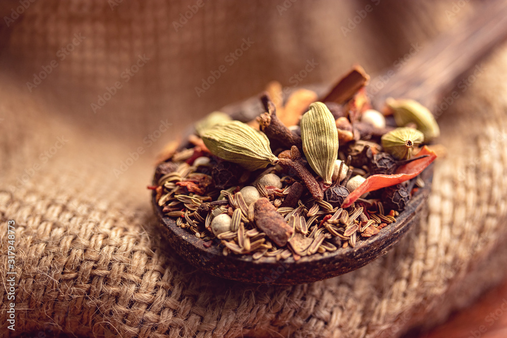 mix spices and herbs in a wooden spoon on dark background, Indian spices food and cuisine ingredients - obrazy, fototapety, plakaty 