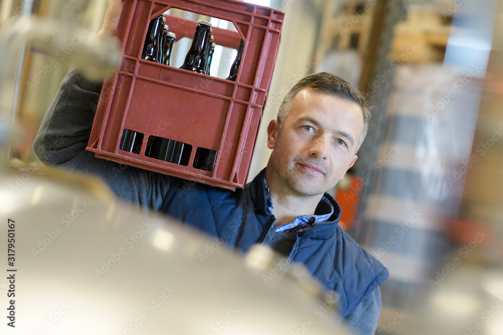 Portrait Of Brewery Worker Carrying Crate Of Beers On Shoulder Foto De portrait-of-brewery-worker-carrying-crate-of-beers-on-shoulder-foto-de