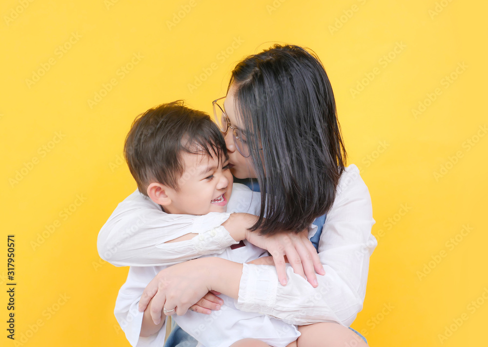 Loving mother and son hugging in studio over yellow background. Loving mother and son hugging in studio over yellow background.