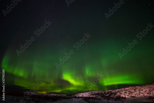 hills, clear starry sky and colorful Northern lights, an incredible natural phenomenon