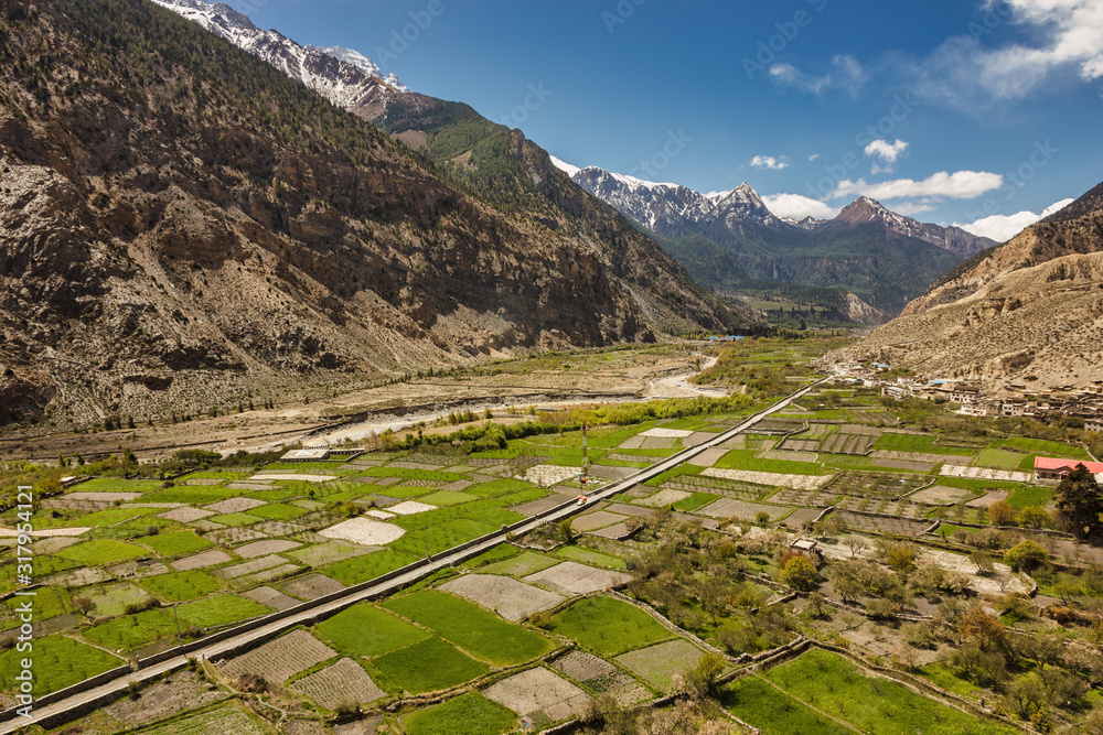 An aerial view of the green fields of the village of Marpha surrounded by mountains on the Annapurna Circuit trail in the region of Mustang in the Nepal Himalayas.