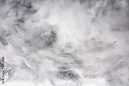 Dense veil of bright white smoke (fog, vapor) on a dark black background, making up intricate beautiful patterns. Fountain clouds