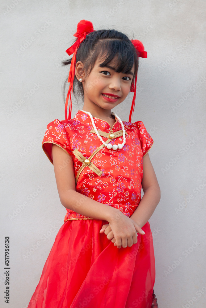 Happy chinese new year. Little girl stand pose and smiled brightly on cement wall background. Happy chinese new year. Little girl stand pose and smiled brightly on cement wall background.