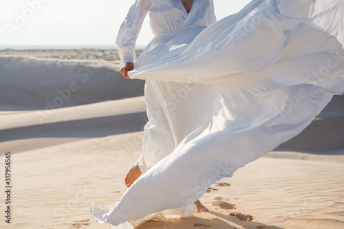 Woman in white wedding dress breazing on the wind in white dunes desert (Soft focus)
