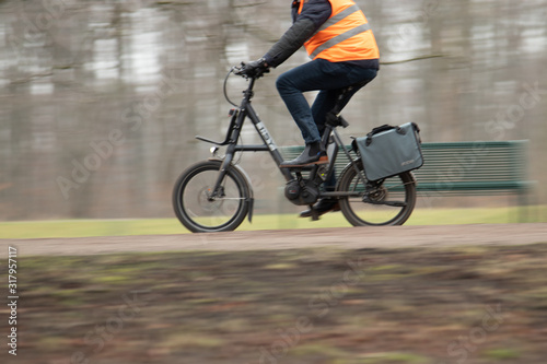 cyclist riding trough a walkway in the park, wearing a reflector jacket