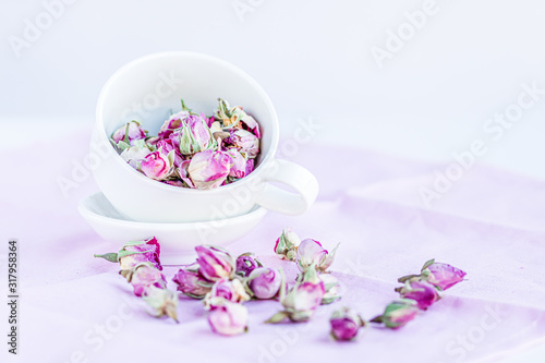 Selective focus on dried roses in a white cup at pink pastel  background. Copy space.