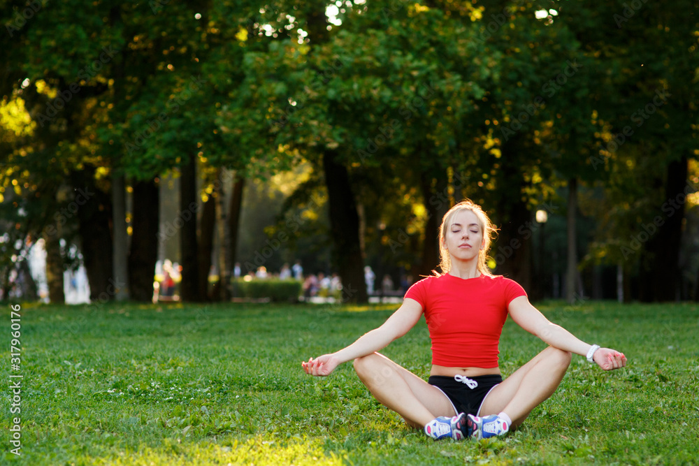 Young beautiful woman doing yoga sitting on the grass in the Park. training and stretching muscles in nature Young beautiful woman doing yoga sitting on the grass in the Park. training and stretching muscles in nature