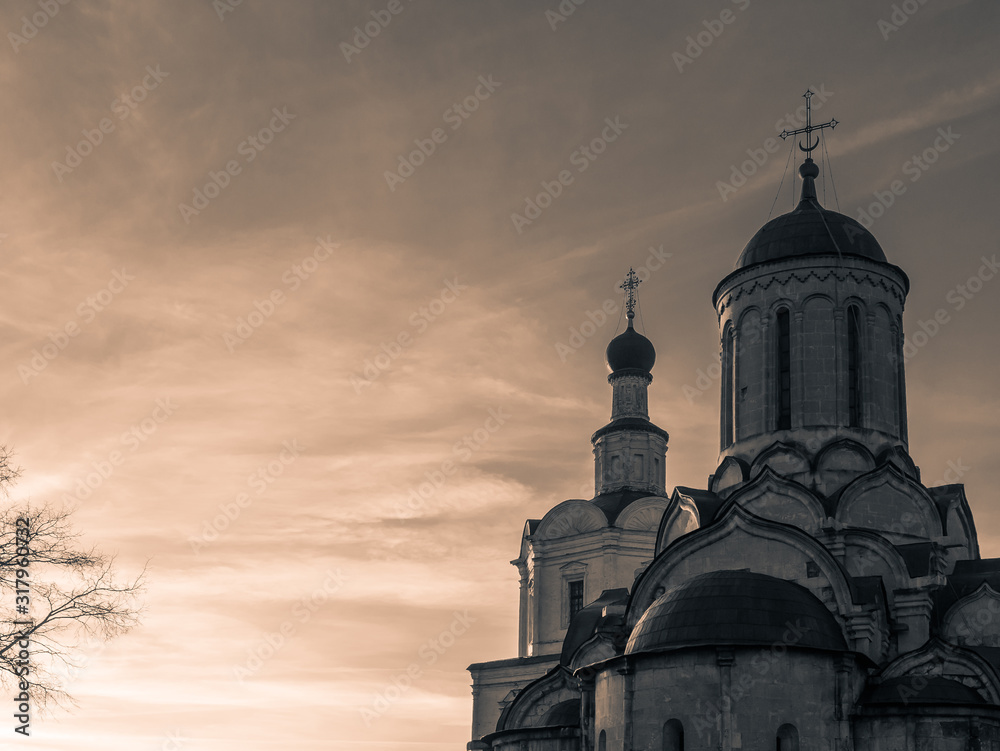 Domes with crosses of ancient churches in a Russian monastery on a sunset sky background