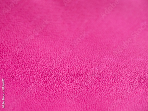 Background with leather texture. Pink piece of natural tanned calfskin painted and treated with fuchsin paint. Shallow depth of field, shot from side with macro lens. Copyspace for border or frame