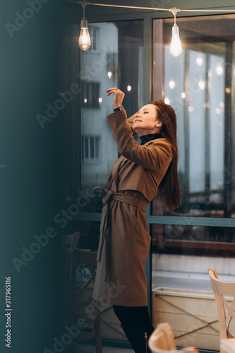 Outdoor fashion portrait of stylish young woman having fun, emotional face , laughing, Urban city street style wearing dark casual trousers, white sweater,creamy coat. and sunglasses Fashion concept.