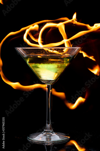 martini glass on black background and lines of fire in the dark