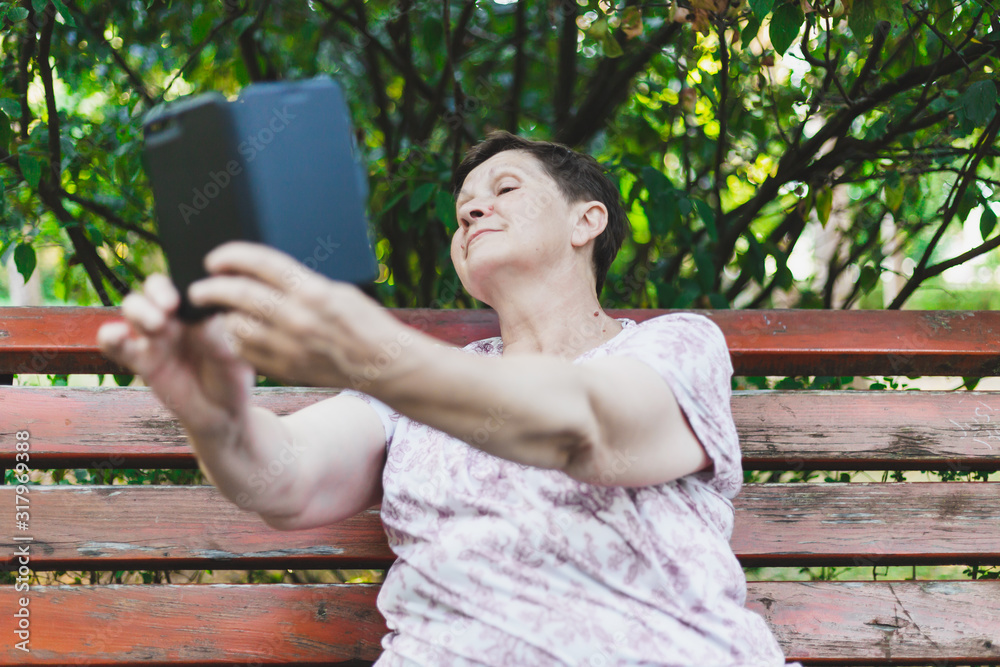 Naklejka premium Senior woman taking selfie outside