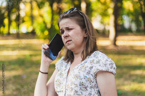 Obraz na plátne Young woman talking on a mobile phone outside