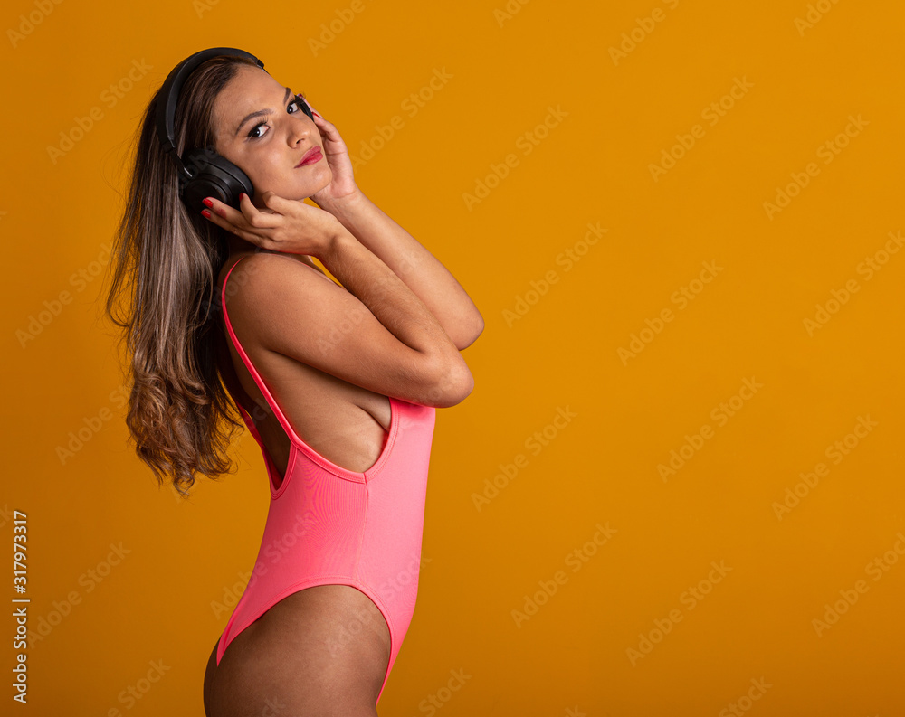 Attractive girl with headphones on a bright yellow background. Dj concept.