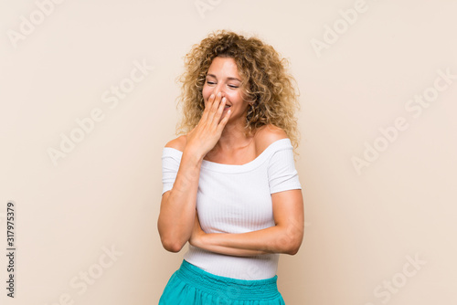Canvas Print Young blonde woman with curly hair over isolated background smiling a lot