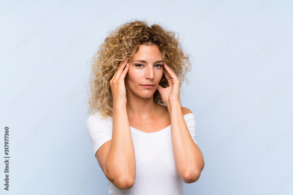 Young blonde woman with curly hair over isolated blue background unhappy and frustrated with something. Negative facial expression Young blonde woman with curly hair over isolated blue background unhappy and frustrated with something. Negative facial expression