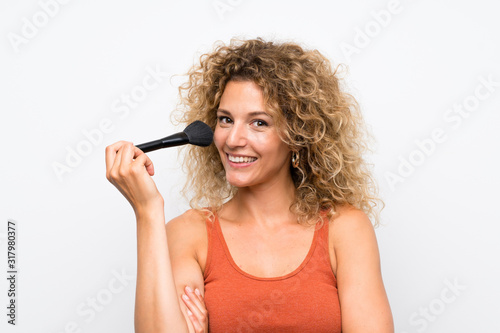 Young blonde woman with curly hair with makeup brush