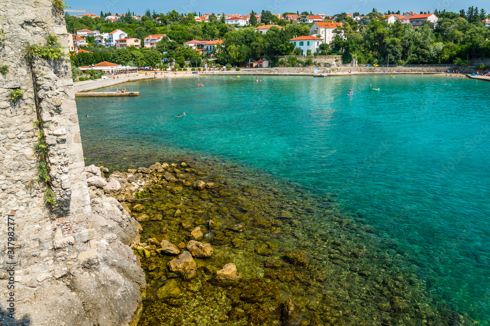 Wall of the fortress with amazing beach in Krk town. Krk town is a famous touristic destination on Krk island, Croatia. Space in right side