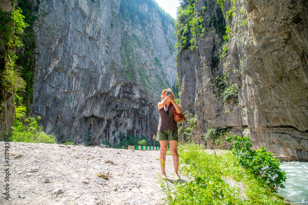 Obraz premium young woman makes selfie on the background of rocks