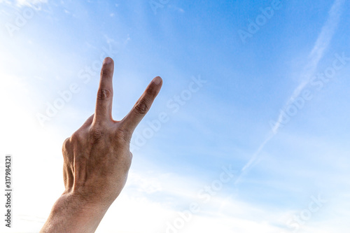 Man's hand showing two fingers up on sky