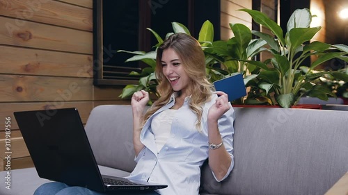 Pretty satisfied 30-aged blondie carefully looking at the computer and waiting for results,then she is happy and clapping her hands photo