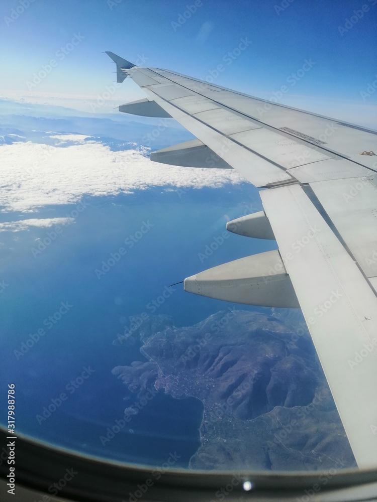 Obraz premium wing of an airplane flying above the clouds