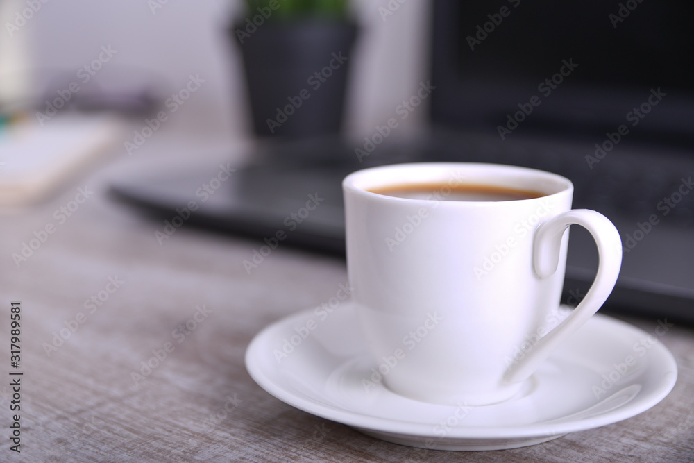 Cup of coffee on office desktop with laptop, computer on wooden table. Close up, with space for your text Cup of coffee on office desktop with laptop, computer on wooden table. Close up, with space for your text