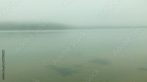 Foggy morning on the lake - waves on the water surface and white fog. photo