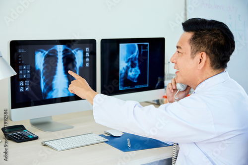 Respiratory therapist discussing medical case with colleague on phone looking on lungs X-Ray image photo