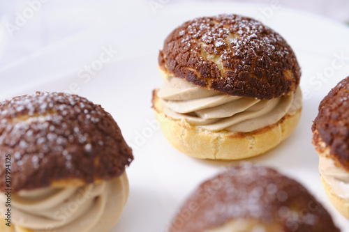 choux cream or cream puff or French profiteroles with fresh cream set on cafe table.